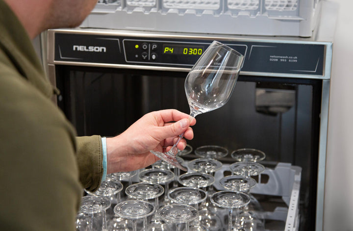 Sparkling wine glass being held in front of Nelson Advantage glass washer